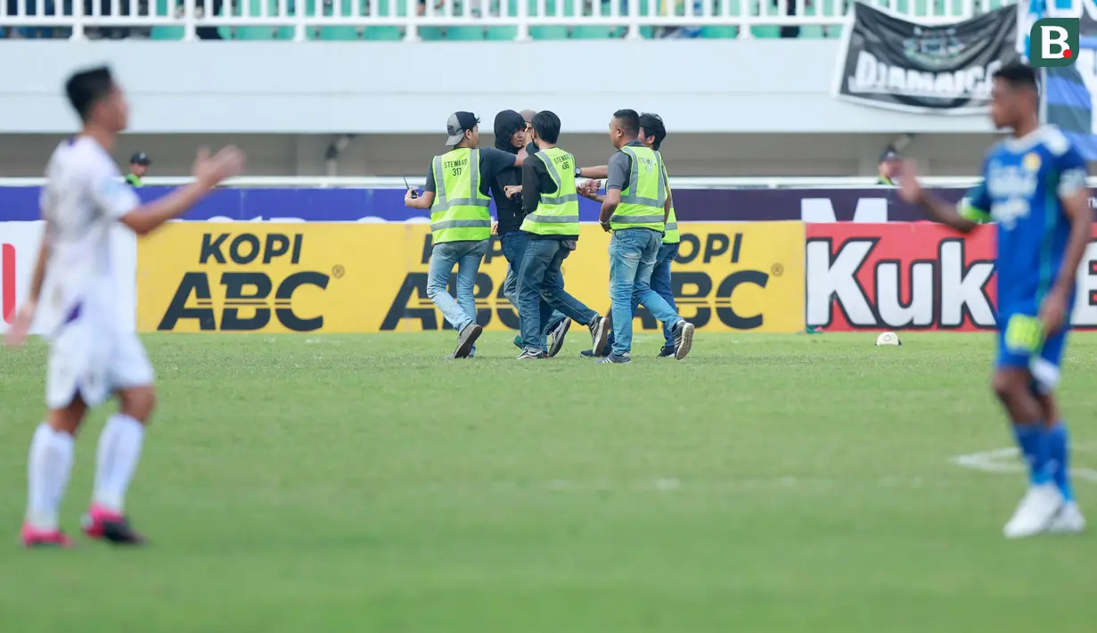 Petugas keamanan berhasil mengamankan oknum suporter nakal yang masuk ke lapangan saat Persib Bandung melawan Persik Kediri pada laga BRI Liga 1 2022/2023 di Stadion Pakansari, Bogor, Rabu (8/3/2023). (Bola.com/M Iqbal Ichsan)