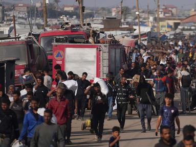 Warga Palestina membawa kotak dan tas berisi makanan dan paket bantuan kemanusiaan yang dikirim oleh Yayasan Kemanusiaan Gaza, organisasi yang didukung Amerika Serikat (AS) dan disetujui oleh Israel, di Khan Younis, Jalur Gaza selatan, Minggu 1 Juni 2025. (AP Photo/Abdel Kareem Hana)