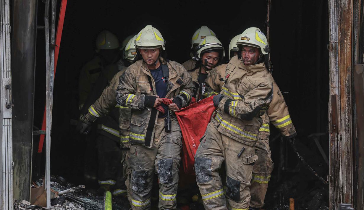 Hingga kini, petugas masih terus melakukan penyisiran ke seluruh bagian gedung hingga lantai enam. Tampak dalam foto, petugas pemadam kebakaran mengevakuasi jenazah korban dari sebuah gedung tujuh lantai di Jakarta Pusat pada Selasa 9 Desember 2025. (SYNATRIA RESPATI/AFP)