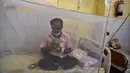 Seorang pasien minum air kelapa saat dia duduk di bawah kelambu di bangsal demam berdarah sebuah rumah sakit pemerintah di Allahabad, India (30/8/2021). (AFP/Sanjay Kanojia)
