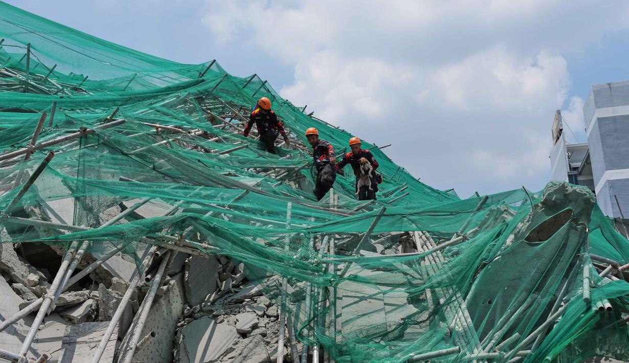 Para penyelamat membawa seekor anjing saat mereka menuruni penyangga yang roboh dari sebuah bangunan yang runtuh di kota Angeles, provinsi Pampanga, utara Manila, Filipina, Senin 25 Mei 2026. (AP Photo/Aaron Favila)