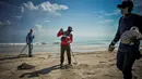 Para pekerja dengan mengenakan masker membersihkan pantai di Havana pada Senin (15/6/2020). Kuba akan menguji semua pelancong untuk Covid-19 dan membatasi kontak mereka dengan penduduk setempat ketika perbatasan dibuka kembali untuk turis asing. (Yamil LAGE / AFP)