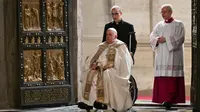 Dari kursi rodanya, Paus Fransiskus mengetuk beberapa kali, dan Pintu Suci Basilika Santo Petrus yang besar berayun terbuka. Paus Fransiskus didorong untuk melintasi ambang pintu itu. (Alberto PIZZOLI/POOL/AFP)