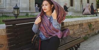 Setelah Lebaran, Prilly Latuconsina tampaknya memilih menikmati waktu liburnya ke Turki. Dalam foto ini, ia terlihat berpose duduk di bangku berlatar sebuah bangunan, mengenakan kemeja biru lengan panjang, legging hitam, dan syal panjang untuk menutupi rambutnya. Ia juga terlihat membawa sling bag berwarna hitam. Foto: Instagram.