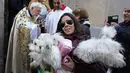 Seorang pendeta memercikkan air suci pada hewan peliharaan di gereja San Anton selama pesta Santo Antonius, santo pelindung hewan, di Madrid, Spanyol, Selasa (17/1/2023). Pesta itu dirayakan setiap tahun di banyak bagian Spanyol dan orang-orang membawa hewan mereka ke gereja untuk diberkati. (AP Photo/Paul White)