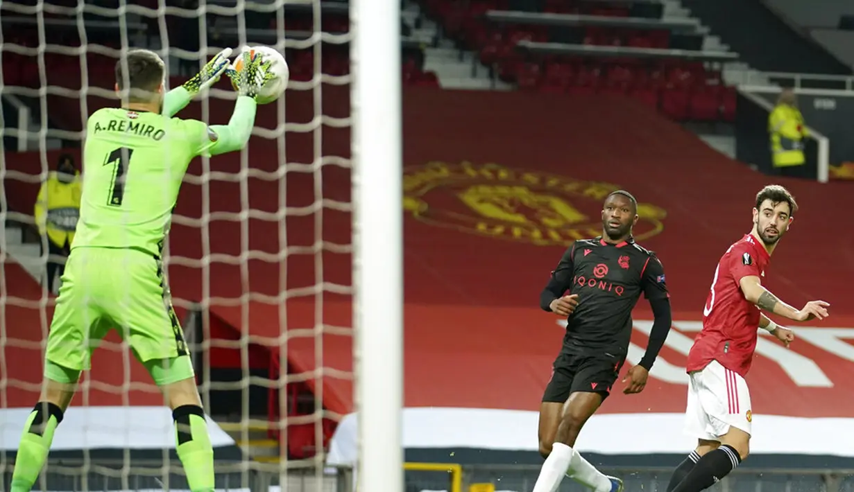Pemain Manchester United Bruno Fernandes (kanan) melepaskan tembakan yang berhasil diselamatkan kiper Real Sociedad Alex Remiro pada pertandingan leg kedua babak 32 besar Liga Europa di Old Trafford, Manchester, Inggris, Kamis (25/2/2021). Laga berakhir 0-0. (AP Photo/Dave Thompson)
