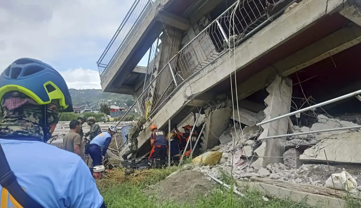 Tim penyelamat mencoba menarik seorang warga yang terperangkap dari bawah reruntuhan bangunan setelah gempa kuat melanda La Trinidad, Provinsi Benguet, Filipina, 27 Juli 2022. Guncangan gempa menyebabkan banyak tembok rumah dan bangunan yang retak, termasuk beberapa runtuh. (Bureau of Fire Protection via AP)