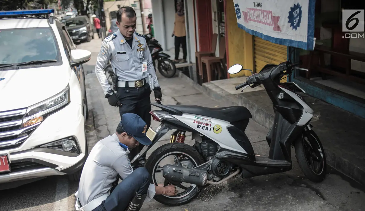 Petugas Dishub DKI Jakarta merazia  kendaraan roda dua dengan mencopot pentil yang terparkir di trotoar di kawasan Cipete Raya, Jakarta, Selasa (13/8/2019). Razia tersebut dilakukan Dishub untuk mengembalikan fungsi trotoar untuk pejalan kaki. (Liputan6.com/Faizal Fanani)