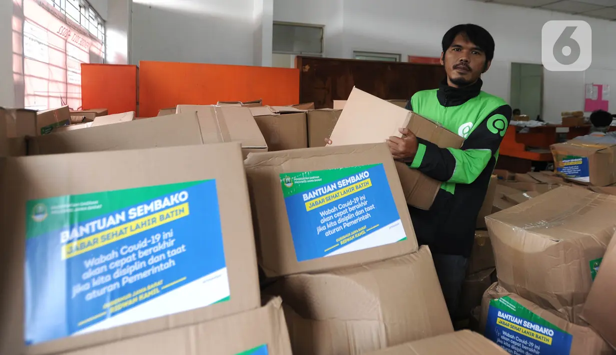 Pengemudi ojek online mengemas bansos untuk warga yang terdampak COVID-19 di Kantor Pos, Cibinong, Bogor, Jawa Barat, Senin (20/4/2020). Bansos khususnya disalurkan di zona merah persebaran yaitu Bogor, Depok, dan Bekasi dengan memberdayakan ojek online. (merdeka.com/Arie Basuki)