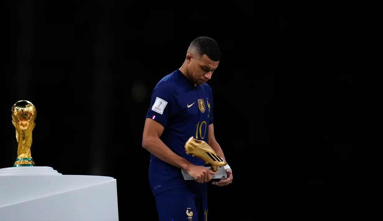 Pemain Prancis Kylian Mbappe memegang trofi Sepatu Emas saat melewati trofi Piala Dunia 2022 usai melawan Argentina pada pertandingan sepak bola final Piala Dunia 2022 di Stadion Lusail, Lusail, Qatar, 18 Desember 2022. Kylian Mbappe berhak membawa pulang trofi penghargaan Sepatu Emas setelah menjadi pencetak gol terbanyak selama gelaran Piala Dunia 2022. (AP Photo/Petr David Josek)