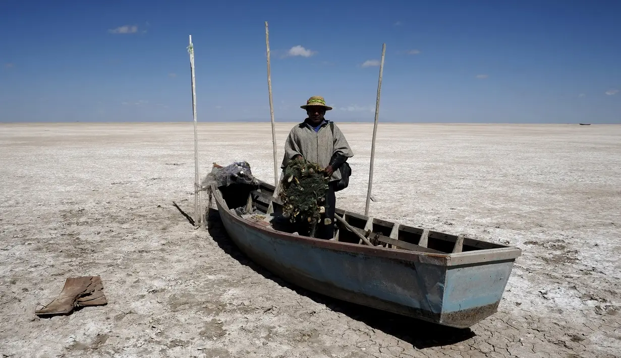 Seorang nelayan dari kelompok etnik Urus berdiri di atas perahunya yang tergeletak di Danau Poopo, La Paz, Bolivia, (17/12). Banyak nelayan kehilangan pekerjaannya akibat keringnya danau ini. (REUTERS/David Mercado)