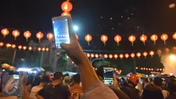 Warga mengambil gambar kembang api yang meluncur di kawasan Pasar Gedhe Surakarta saat perayaan Imlek, Surakarta, Sabtu (28/01). Grebeg Soediro adalah  tradisi  tahunan alkuturasi  budaya  Jawa dan  Cina. (Liputan6.com/Gholib)  