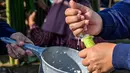 Seorang peserta mengisi tabung bambu dengan beras ketan, yang kemudian diisi dengan santan dan diletakkan di atas api unggun untuk membuat hidangan tradisional yang dikenal sebagai lemang, selama acara memasak massal di Blang Pidie, Kabupaten Aceh Barat Daya, Aceh, pada Sabtu 25 April 2026. (CHAIDEER MAHYUDDIN/AFP)
