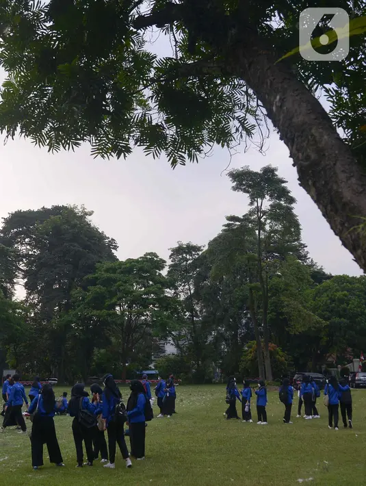 Mahasiswa berfoto di rumput yang bercampur dengan kapas di halaman Institut Pertanian Bogor, Kota Bogor, Jawa Barat, Kamis (25/8/2022). Kapas yang berasal dari pohon kapuk randu yang sedang berguguran itu menjadi daya tarik bagi warga untuk berswafoto. (Liputan6.com/Angga Yuniar)