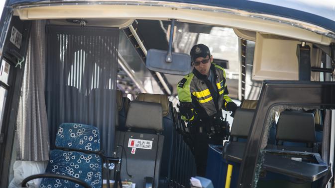 Polisi mengecek bus usai bertabrakan dengan taksi di Hong Kong (30/11). Bus tersebut dalam perjalanan ke bandara Hong Kong bertabrakan dengan taksi, kata polisi, dengan penumpang dilaporkan terlempar dari jendela bus. (AFP Photo/Anthony Wallace)