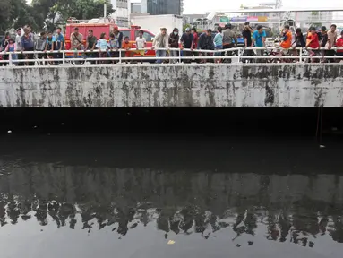 Warga melihat petugas melakukan pencarian buaya di Kali Grogol, Jakarta Barat, Jumat (29/6). Pencarian buaya sempat membuahkan hasil pada hari ketiga, namun kondisi teknis lapangan membuat predator itu kembali lepas. (Liputan6.com/Arya Manggala)