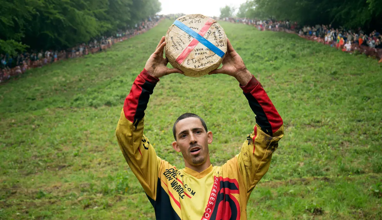 Chris Anderson memegang hadiah setelah berhasil memecahkan rekor dalam kompetisi Cheese Rolling di Cooper's Hill di Brockworth, Gloucestershire, Inggris, Senin (28/5). (Aaron Chown/PA via AP)