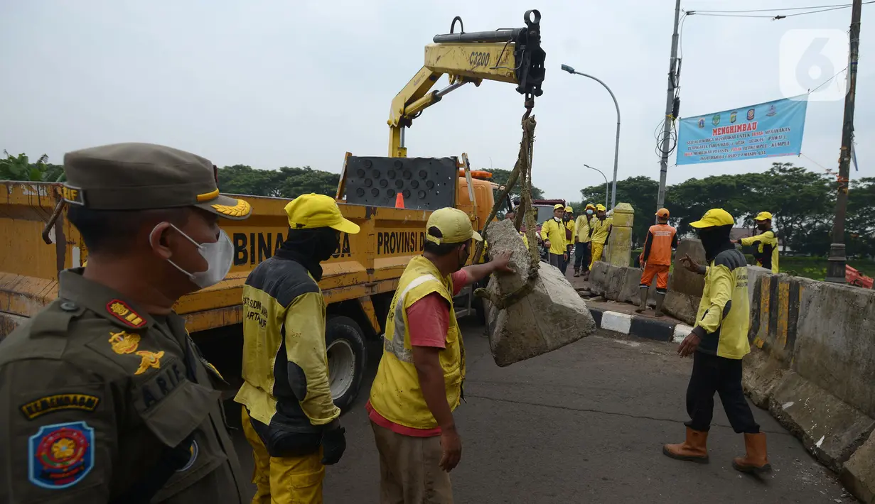 Petugas gabungan memindahkan beton pembatas dengan alat berat di Jalur Inspeksi Kanal Banjir Timur (KBT), Cipinang, Jakarta Timur, Kamis (30/12/2021). Kawasan KBT ditutup guna mencegah kerumunan warga yang hendak merayakan malam pergantian tahun. (merdeka.com/Imam Buhori)
