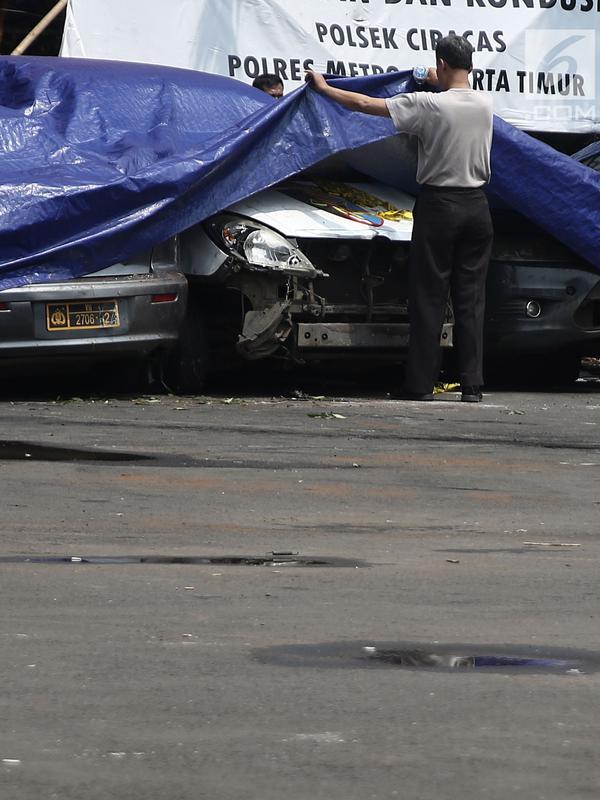 Petugas melihat melihat kondisi mobil yang dirusak di Polsek Ciracas, Jakarta, Rabu (12/12). Pelayanan di Polsek Ciracas lumpuh pascapembakaran oleh massa. (Liputan6.com/Herman Zakharia)