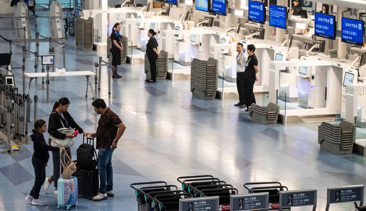 Penumpang menunggu di dekat konter check-in yang kosong di Terminal Internasional Bandara Haneda setelah penerbangan dibatalkan atau ditunda karena badai tropis Jangmi di Tokyo, Jepang, Rabu 3 Juni 2026. (Andrew CAALLERO-REYNOLDS/AFP)