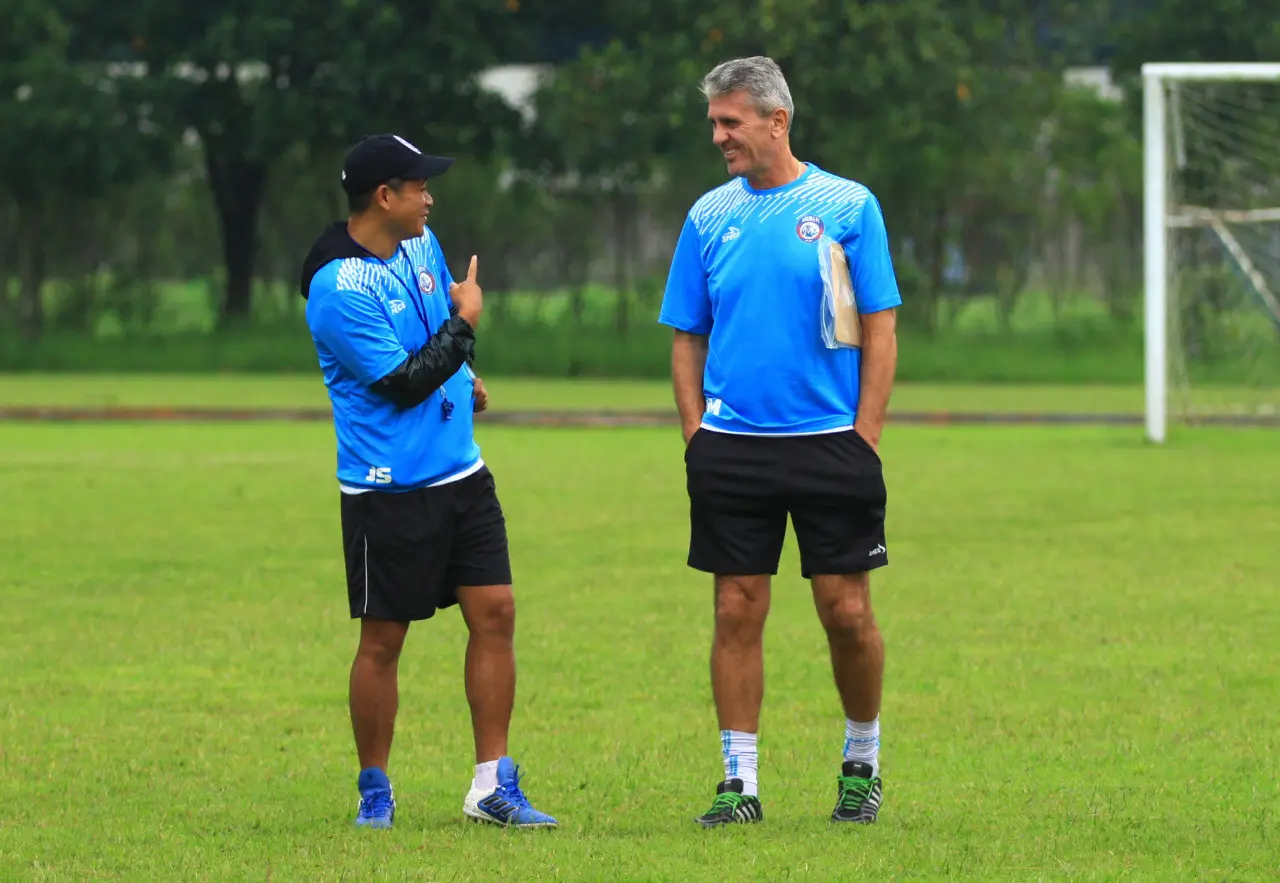 Pelatih kepala Arema FC Joko Susilo tengah berbincang dengan pelatih fisik Dusan Momcilovic. (Liputan6.com/Rana Adwa)