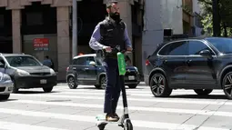 Seorang pria mengendarai skuter bermotor di jalanan di San Francisco (17/4). Pemberhentian operasi skuter bermotor ini karena belum adanya kepastian terhadap keamanan dan keselamatan penggunaan skuter di tempat umum. (AP/Jeff Chiu)