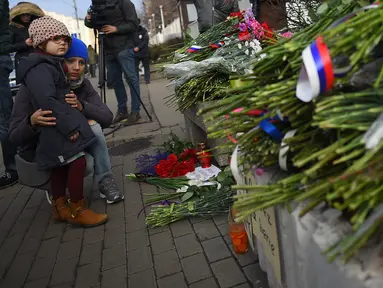 Warga Moskow melihat karangan bunga di luar Kedutaan Besar Prancis di Moskow, Sabtu (14/11/2015) . Karangan bunga tersebut untuk menghormati para korban serangan mematikan di Paris. (AFP Photo/Dmitry Serebryakovi)