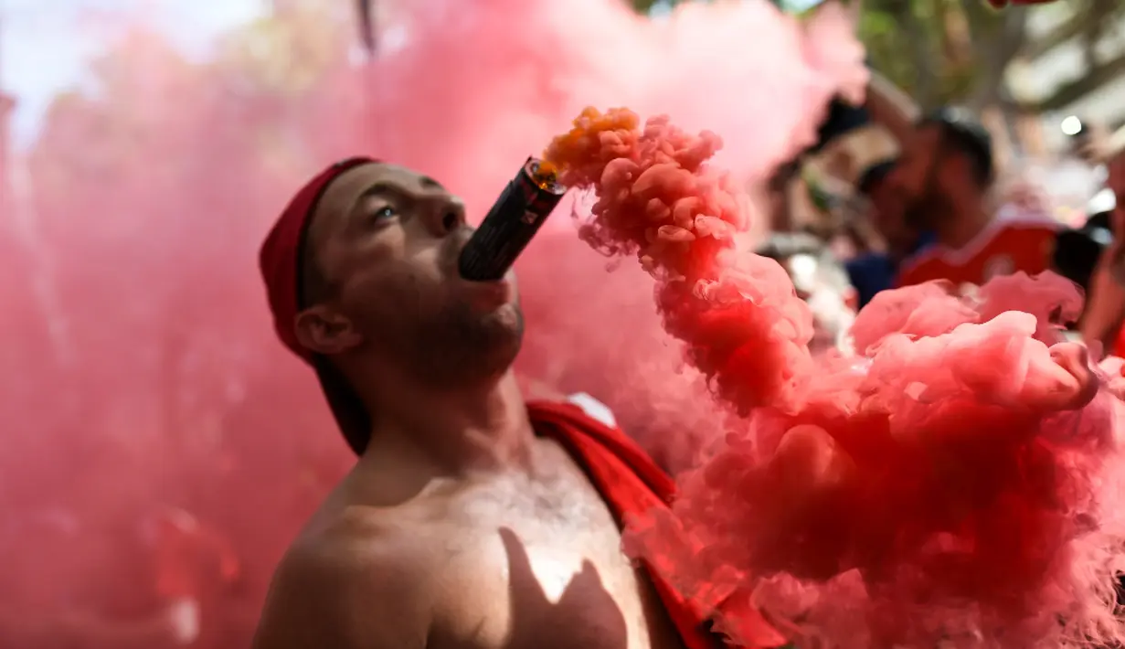 Seorang suporter Wales meletakkan suar di mulutnya setelah timnya lolos ke 16 Besar Piala Eropa 2016. (AFP/Bulent Kilic)