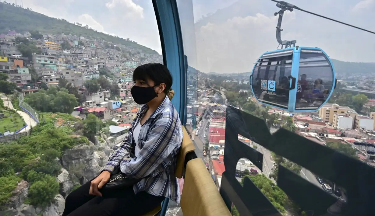 Penumpang melakukan perjalanan dengan sistem kereta gantung yang dijuluki Cablebus setelah peresmiannya di pinggiran Mexico City, Meksiko, 12 Juli 2021. Sistem kereta gantung ini memudahkan penumpang untuk melakukan perjalanan dari Cuautepec menuju pusat kota. (PEDRO PARDO/AFP)