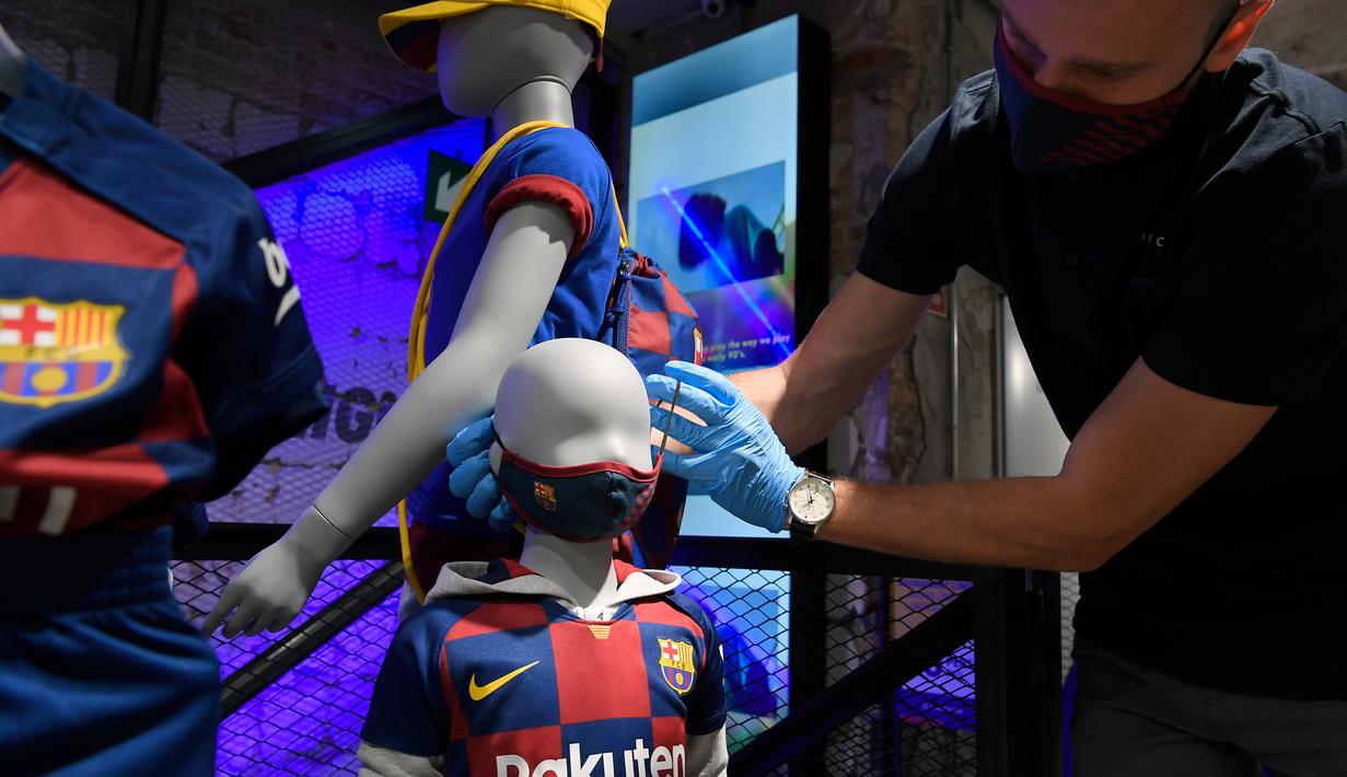 Penjaga toko memasang masker berlogo Barcelona ke Manekin di Toko Asesoris Barcelona, Senin (25/5/2020). Di tengah pandemi virus Corona, Barcelona menjual masker dengan harga 18 euro atau sekitar Rp 291 ribu. (AFP/Lluis Gene)