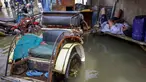 Seorang pria tertidur di samping becak, kendaraan roda tiga bertenaga manusia, sementara air pasang membanjiri jalanan di Muara Baru, Jakarta pada Sabtu 6 Desember 2025. Banjir rob akibat air pasang laut yang tinggi merendam jalanan dan pemukiman di kawasan Muara Baru, Penjaringan, Jakarta Utara sejak beberapa hari lalu, dengan puncaknya terjadi pada Jumat 5 Desember 2025. (ADITYA IRAWAN/AFP)