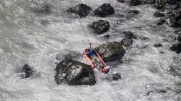 Seorang pria dievakuasi dengan menyeberangi sungai setelah sebuah bus jatuh dari tebing di Pasamayo, Peru, Selasa (3/1). Bus  yang membawa sekitar 53 penumpang tersebut jatuh ke dalam jurang setinggi 100 meter. (Vidal Tarky, Andina News Agency via AP)