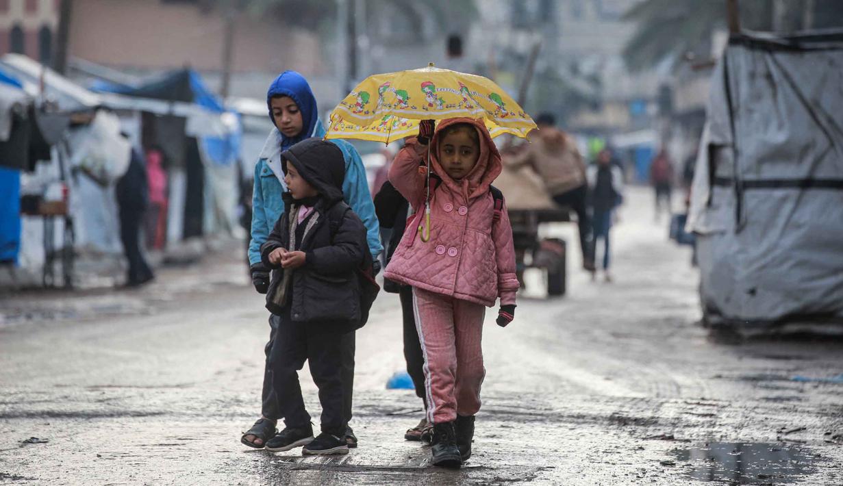 Sebelumnya, sistem pendidikan di Gaza berada di ambang kehancuran, dengan lebih dari 97% sekolah dilaporkan rusak atau hancur. Tampak dalam foto, seorang gadis kecil yang memegang payung pergi ke sekolah di Deir al-Balah, di Jalur Gaza tengah, pada 10 Desember 2025. (BASHAR TALEB/AFP)