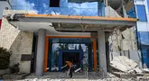 Pekerja membersihkan puing-puing dari sebuah gedung bank yang rusak akibat gempa berkekuatan magnitudo 7,7 di Ruteng, Manggarai, Nusa Tenggara Timur, Minggu, 16 Agustus 2026. (AFP/ Juni Kriswanto)