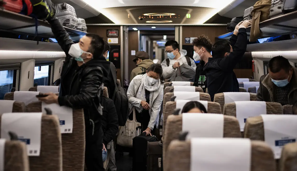 Penumpang dengan mengenakan masker menaiki kereta api menuju Beijing di stasiun kereta Wuhan, provinsi Hubei, Rabu (15/4/2020). Usai status lockdown dicabut, orang-orang yang sebelumnya berada di Wuhan perlahan mulai meninggalkan kota, salah satu tujuannya adalah Beijing.  (NOEL CELIS/AFP)