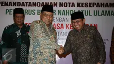 Ketua Umum PBNU, Said Aqil Siradj (tengah) bersalaman dengan Ketua Dewan Komisioner  OJK Muliaman D. Hadad  di Jakarta, (29/2). Kerjasama meliputi pengembangan sektor jasa keuangan dan beberapa hal terkait lembaga keuangan. (Liputan6.com/Angga Yuniar)