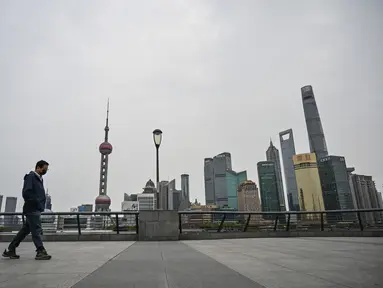 Seorang pria berjalan di sepanjang Sungai Huangpu di distrik Pudong yang dikunci sebagai tindakan melawan Covid-19, di Shanghai (28/3/2022).  Shanghai  lockdown setiap setengah kota secara bergiliran untuk tes Covid-19 massal mulai Senin (28/3/2022) di tengah lonjakan infeksi. (AFP/Hector Retamal)