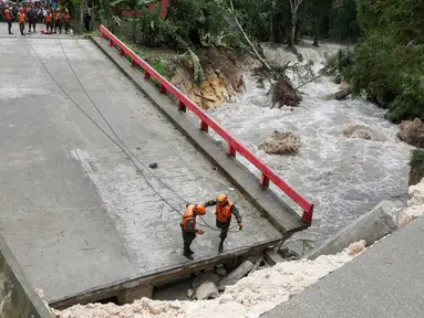 Tim penyelamat Guatemala berdiri di jembatan yang ambruk disebabkan oleh Badai Earl di Menchor de Mencos, Guatemala (4/8). Badai Earl menimbulkan hujan lebat, banjir dan angin kencang di sejumlah negara di Amerika Tengah. (REUTERS/Luis Echeverria)