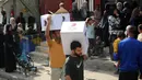 Pria-pria Palestina masing-masing membawa satu kotak makanan, yang dikumpulkan di pusat distribusi di kamp pengungsi Nuseirat, di pusat Jalur Gaza pada 2 November 2025. PBB menegaskan bahwa semua pihak harus menahan diri dari tindakan yang dapat membahayakan warga sipil dan pekerja kemanusiaan. (EYAD BABA/AFP)