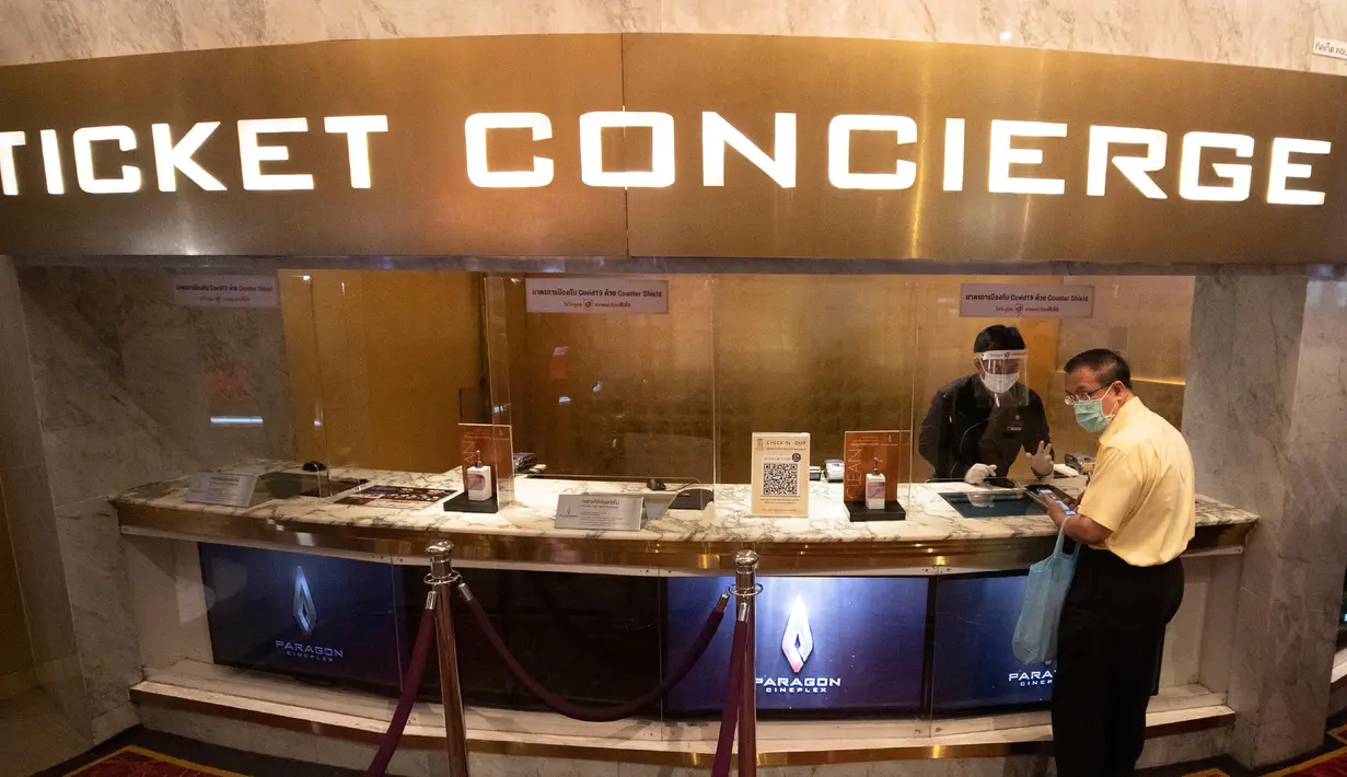 Pengunjung bioskop memakai masker untuk membantu mencegah penyebaran Covid-baru penyebab Covid-19 ketika ia membeli tiket di bioskop Paragon Cineplex di Bangkok, Thailand, Senin (1/6/2020).  Kebijakan itu menyusul penurunan jumlah kasus penularan Covid-19. (AP Photo/Sakchai Lalit)