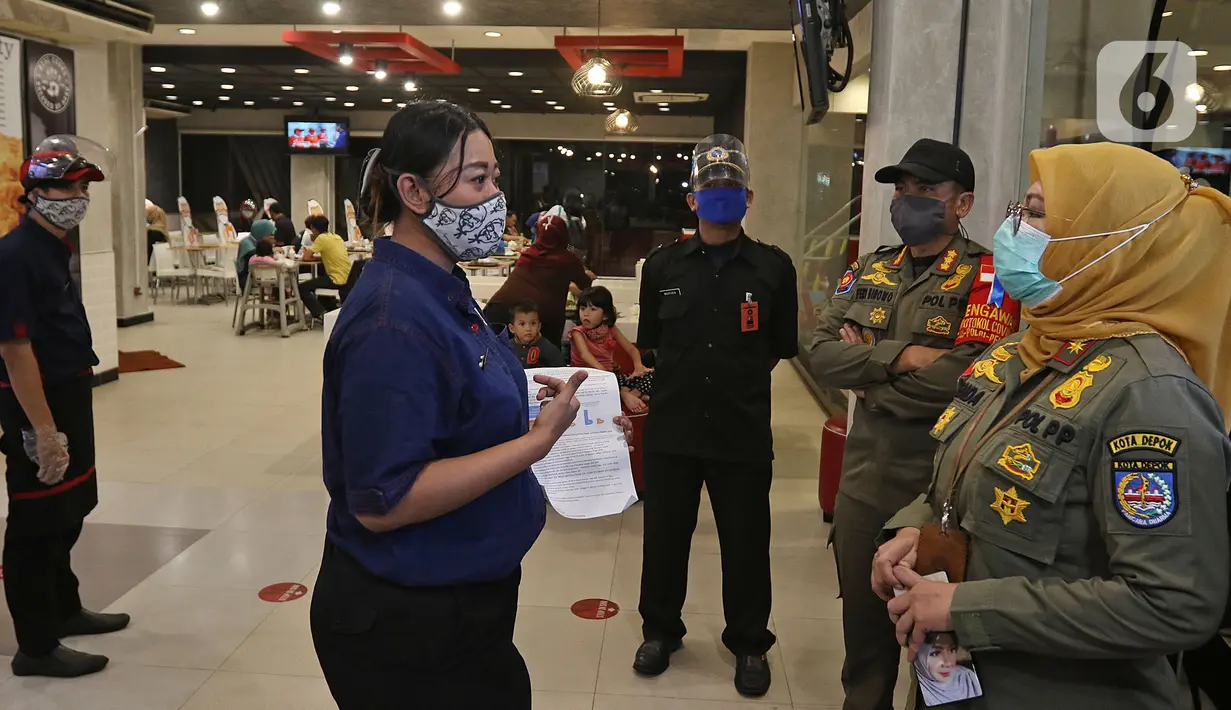 Petugas melakukan sosialisasi aturan jam malam di sepanjang Jalan Margonda, Depok, Senin (31/8/2020). Sosialisasi aturan jam malam dilakukan selama 3 hari di kawasan Depok yang diberlakukan mulai malam hari ini guna meminimalisir penyebaran covid-19. (Liputan6.com/Herman Zakharia)