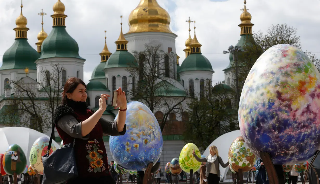 Pengunjung memotret telur Paskah yang dipajang di depan Katedral Mikhaylivsky di pusat Kiev sebelum perayaan Paskah, Ukraina, Rabu (12/4). Sebanyak 500 seniman tradisonal Ukraina terlibat dalam pembuatan telur paskah ini. (AP Photo / Sergei Chuzavkov)
