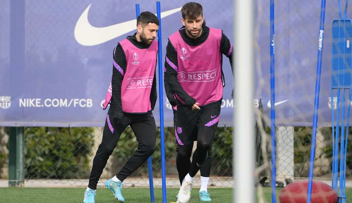 Bek Barcelona Jordi Alba (kiri) dan Gerard Pique mengambil bagian dalam sesi latihan di Barcelona pada 16 Februari 2022. Barcelona bakal meladeni Napoli pada leg pertama play-off babak gugur Liga Europa 2021/22 di Camp Nou, Jumat 18 Februari 2022. (LLUIS GENE / AFP)
