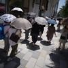 Orang-orang berjalan di trotoar di bawah terik matahari di Tokyo, Selasa (28/6/2022). Pejabat cuaca juga mengumumkan akhir paling awal musim hujan dalam beberapa dekade. (AP Photo/Eugene Hoshiko)