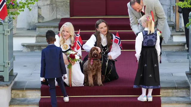 Putri Mahkota Mette-Marit (kiri), Putra Mahkota Haakon-Magnus (kanan), dan Putri Ingrid Alexandra (tengah) menyambut pawai anak-anak selama perayaan 17 Mei di kediaman mereka, Skaugum, sebelah barat ibu kota Norwegia, Oslo, pada 17 Mei 2024.