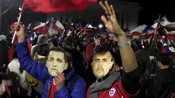 Suporter Chili berkumpul di jalan memakai topeng Alexis Sanchez (kiri) dan Arturo Vidal merayakan kemenangan Chili atas Peru di Copa Amerika 2015 di kota Santiago, (29/6/2015). Chile melaju ke final usai mengalahkan Peru 2-1. (REUTERS/Jorge Adorno)