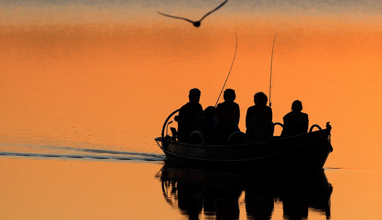 Nelayan lokal mengayuh perahu saat matahari terbenam di danau Lusiai dekat kota kecil Ignalina, sekitar 120 km (74,5 mil) utara ibukota Vilnius, Lithuania (3/6/2019). (AP Photo/Mindaugas Kulbis)