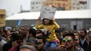 Seorang anak digendong orang tuanya selama unjuk rasa Pekerja Otoritas Palestina di alun-alun Kota Gaza, Sabtu (8/4). Aksi ini sebagai bentuk protes melawan kebijakan Otoritas Palestina yang melakukan pemotongan gaji bagi pegawai di Gaza (MAHMUD HAMS/AFP)