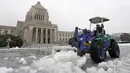 Seorang pria menggunakan alat berat untuk membersihkan salju di halaman Gedung Diet di Tokyo, Jepang, Senin (18/1). Akibat banyaknya tumpukan salju yang menyelimuti daerah metropolitan Tokyo, moda transportasi massa pun lumpuh. (AFP/JIJI Press Japan Out)