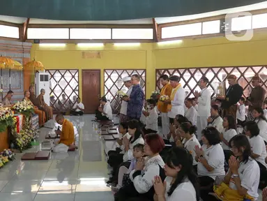 Umat Buddha mengikuti prosesi Puja Bakti di Wihara Arya Dwipa Arama, Taman Mini Indonesia Indah (TMII), Jakarta, Senin (12/5/2025). (Liputan6.com/Herman Zakharia)